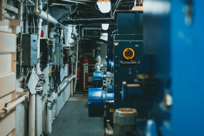 A detailed view of industrial machinery and pipes in a maintenance corridor.