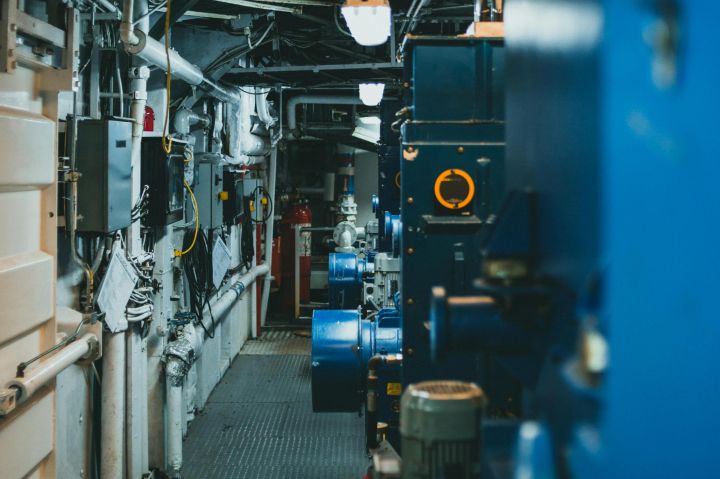 A detailed view of industrial machinery and pipes in a maintenance corridor.